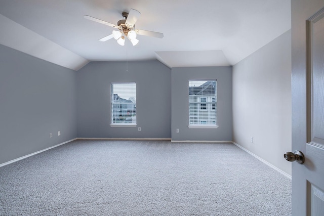 carpeted spare room with baseboards, lofted ceiling, and a ceiling fan