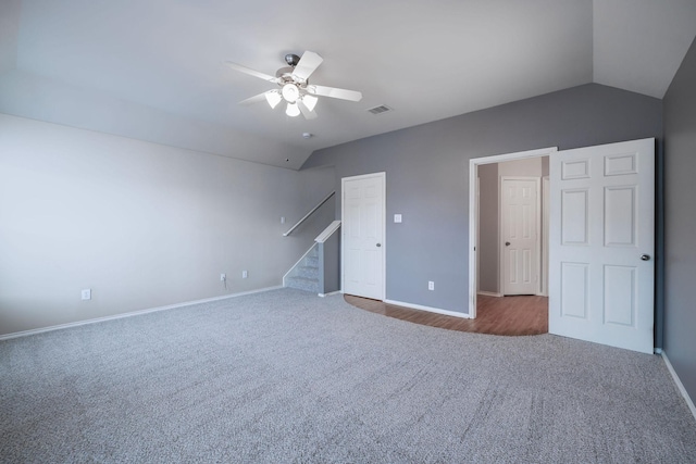 interior space with a ceiling fan, baseboards, visible vents, stairs, and vaulted ceiling