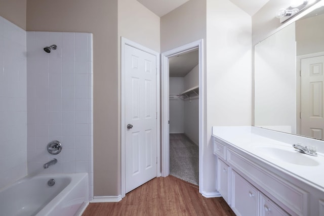 full bath with a spacious closet, baseboards, shower / bath combination, wood finished floors, and vanity