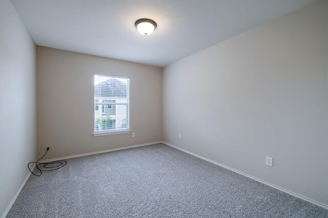 carpeted spare room featuring baseboards