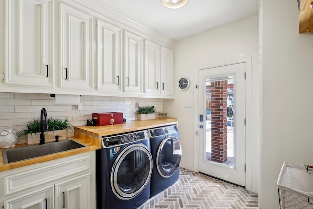 washroom featuring cabinet space, separate washer and dryer, brick floor, and a sink