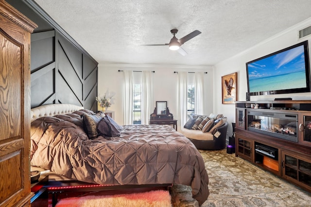 bedroom with a ceiling fan, a textured ceiling, ornamental molding, and carpet flooring