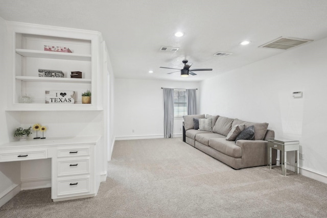 living area featuring light carpet, built in desk, and visible vents