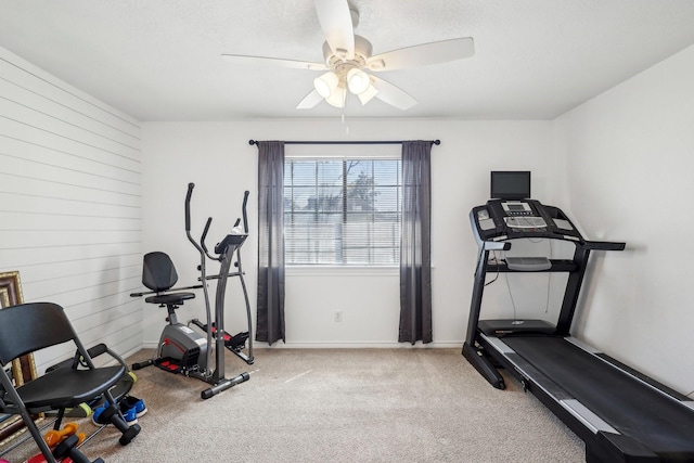 workout room with wood walls, baseboards, a ceiling fan, and carpet floors