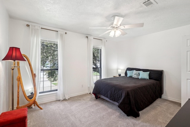 carpeted bedroom with multiple windows, a ceiling fan, and visible vents