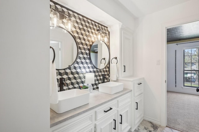 bathroom featuring a sink, baseboards, marble finish floor, and double vanity