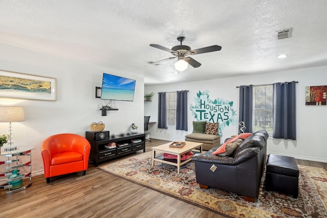 living area featuring baseboards, a textured ceiling, wood finished floors, and a ceiling fan