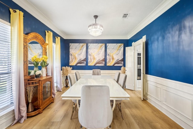 dining area with a notable chandelier, visible vents, light wood finished floors, and wainscoting