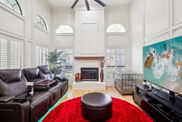 living room with crown molding, a decorative wall, wood finished floors, and a towering ceiling