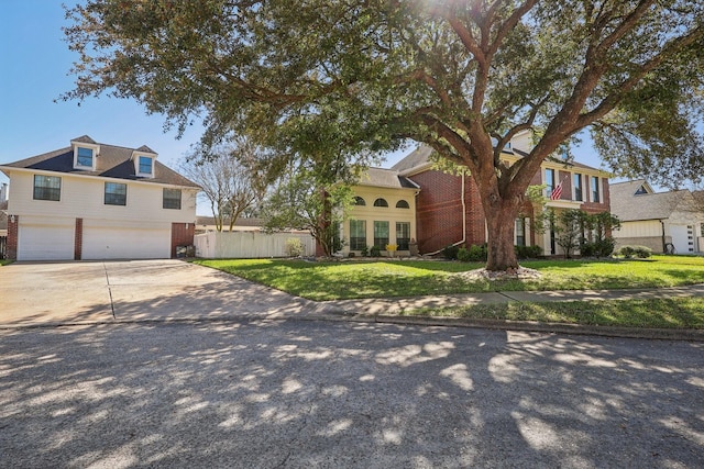 view of front of house with a front yard, fence, driveway, an attached garage, and brick siding