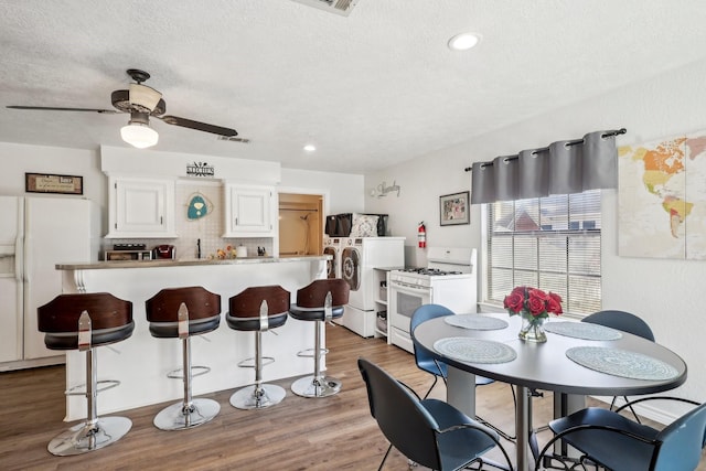 dining room with a ceiling fan, a textured ceiling, wood finished floors, recessed lighting, and washer / dryer