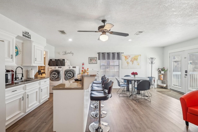 kitchen with a sink, visible vents, dark wood-type flooring, and washing machine and dryer