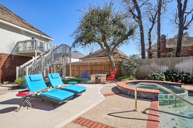 view of patio / terrace with a wooden deck, a fenced backyard, a pool with connected hot tub, stairs, and a fire pit