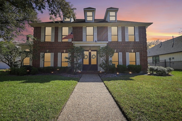 view of front of home with a yard, french doors, and brick siding