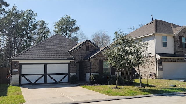 view of front of home featuring a front yard, driveway, roof with shingles, an attached garage, and brick siding