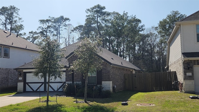 exterior space featuring fence, driveway, an attached garage, a lawn, and brick siding