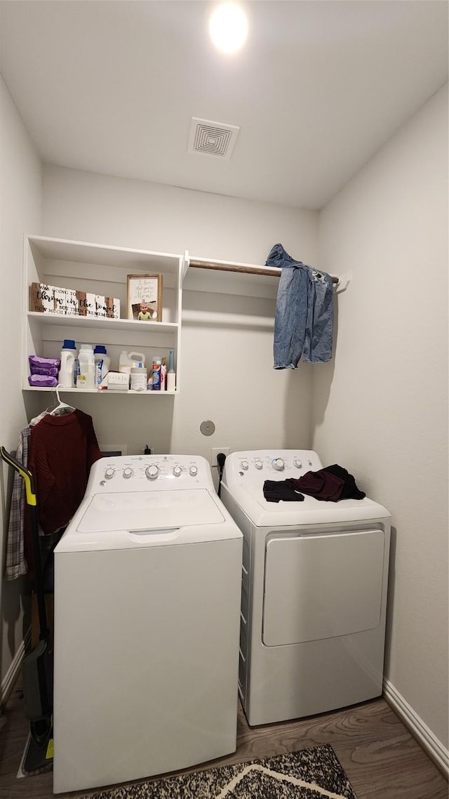 clothes washing area featuring laundry area, wood finished floors, visible vents, and washing machine and clothes dryer