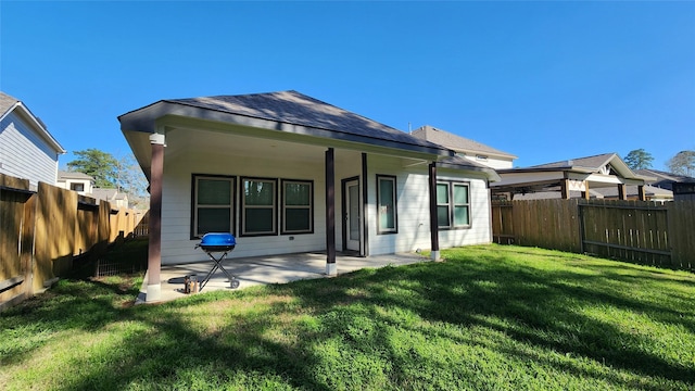 back of house featuring a patio, a yard, and a fenced backyard