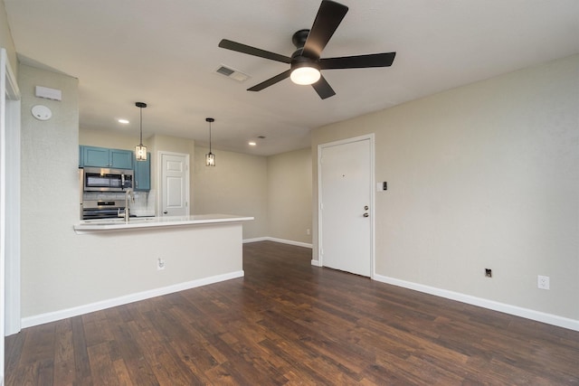 kitchen with stainless steel microwave, blue cabinetry, visible vents, baseboards, and dark wood-style flooring