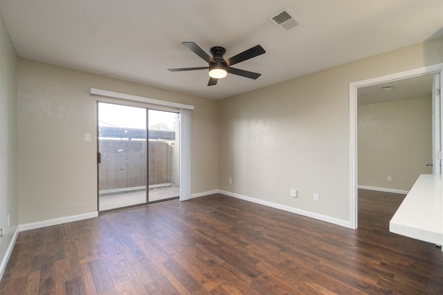 spare room featuring a ceiling fan, dark wood-style floors, visible vents, and baseboards