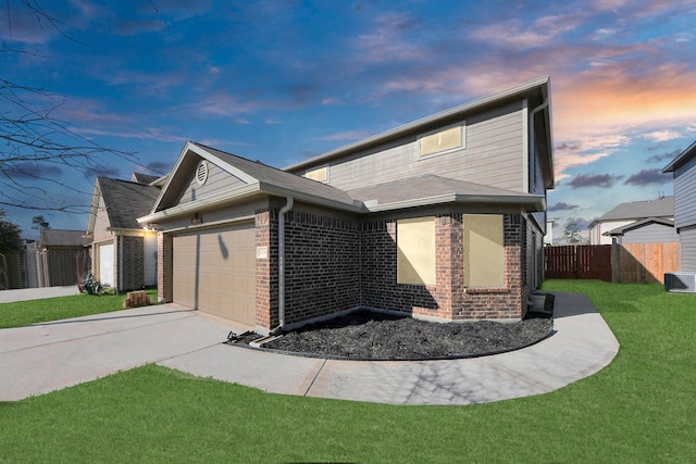 exterior space featuring brick siding, fence, concrete driveway, a garage, and a yard