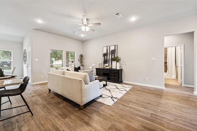 living room with a wealth of natural light, baseboards, visible vents, and light wood finished floors