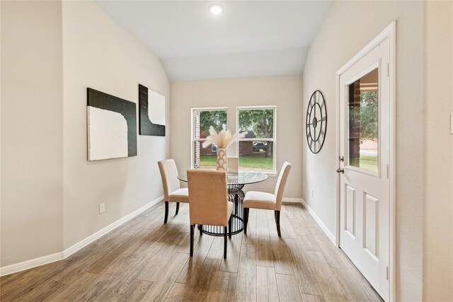 dining room with vaulted ceiling, a healthy amount of sunlight, and wood finished floors