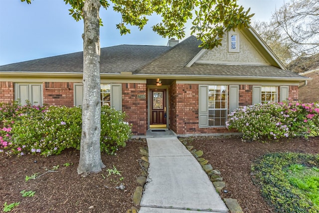 view of front of home featuring stucco siding, brick siding, and a shingled roof