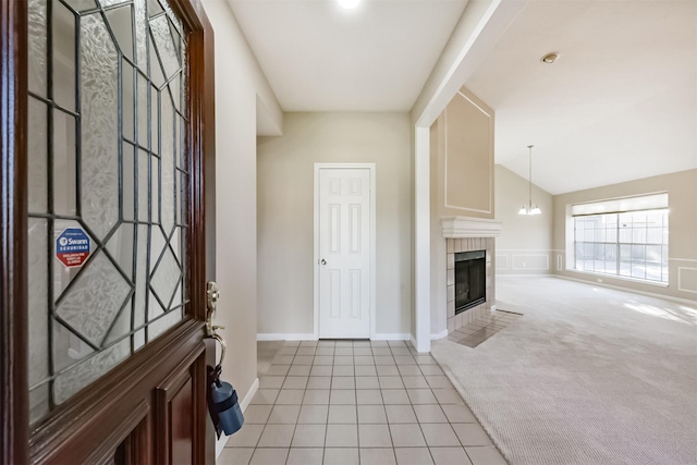 entryway featuring lofted ceiling, light carpet, light tile patterned floors, a tile fireplace, and a notable chandelier