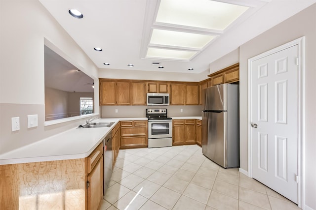 kitchen featuring brown cabinets, a ceiling fan, a sink, stainless steel appliances, and light countertops