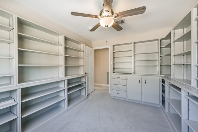 spacious closet with light carpet, visible vents, and a ceiling fan