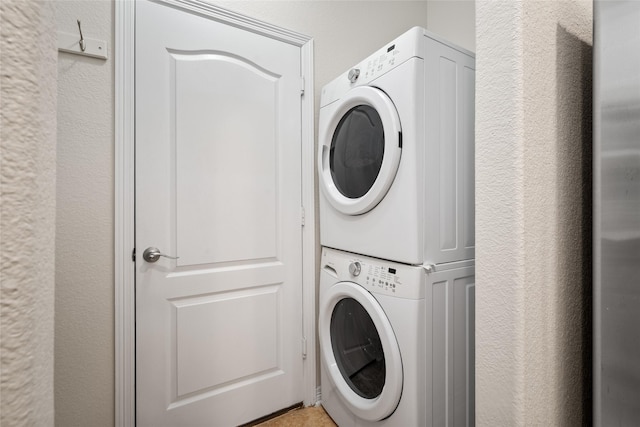 laundry room with stacked washer and dryer, laundry area, and a textured wall