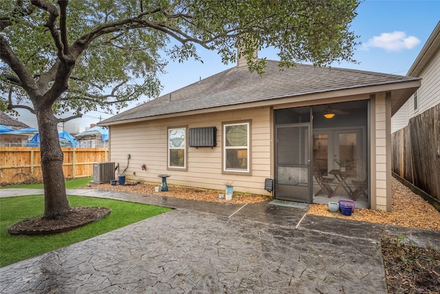 back of property with a shingled roof, central air condition unit, a chimney, a fenced backyard, and a patio