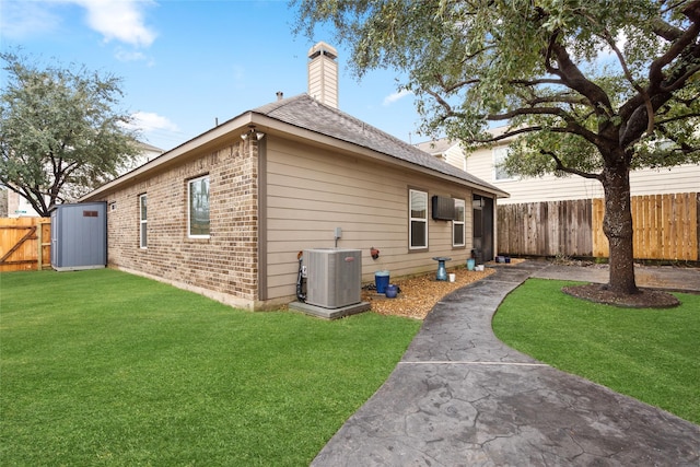 rear view of property featuring brick siding, fence, a lawn, cooling unit, and a chimney