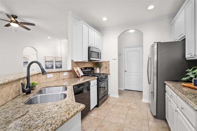 kitchen featuring crown molding, decorative backsplash, arched walkways, black appliances, and a sink