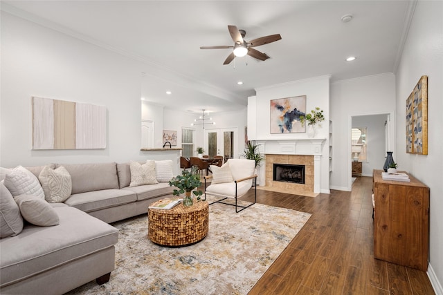 living room with crown molding, baseboards, ceiling fan, a tiled fireplace, and dark wood-style floors