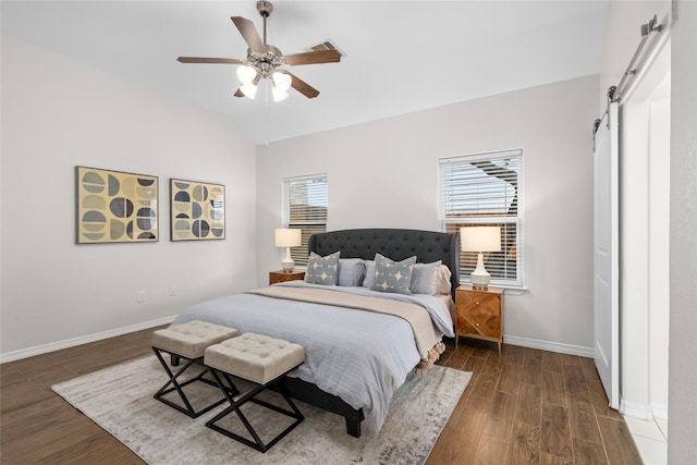 bedroom featuring dark wood finished floors, multiple windows, lofted ceiling, and a barn door