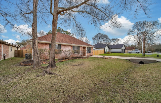 view of front facade with brick siding, a front lawn, fence, roof with shingles, and cooling unit