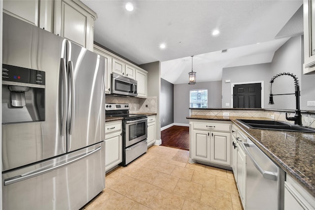 kitchen featuring a sink, tasteful backsplash, stainless steel appliances, a peninsula, and lofted ceiling