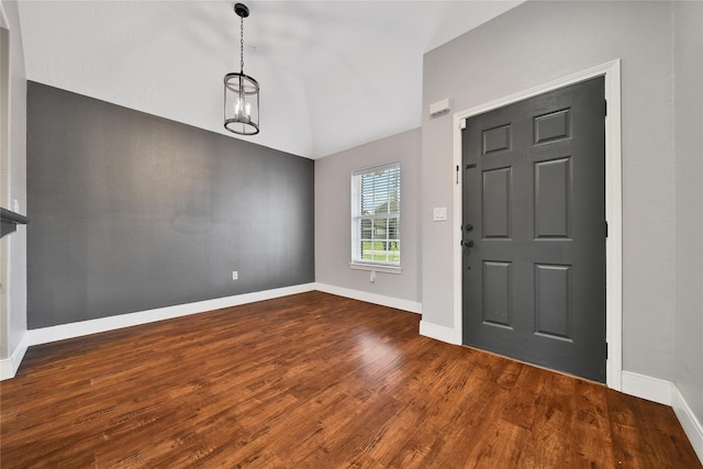 foyer entrance featuring baseboards, lofted ceiling, a notable chandelier, and wood finished floors