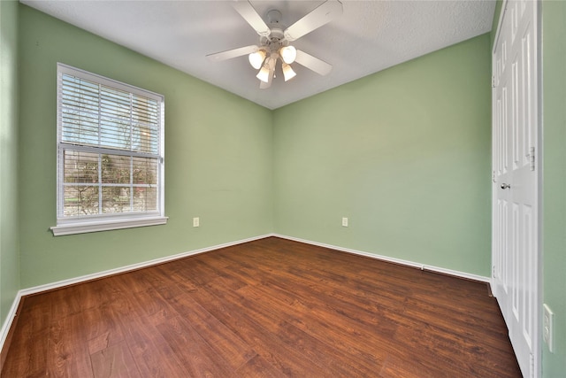 unfurnished room featuring baseboards, dark wood finished floors, and a ceiling fan