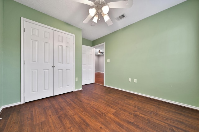 unfurnished bedroom with wood finished floors, visible vents, a closet, and baseboards