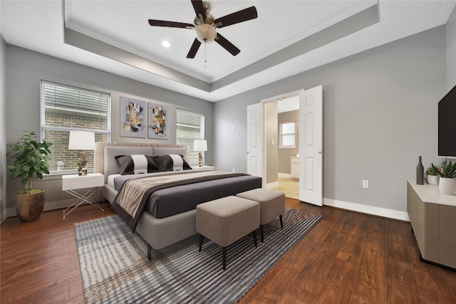 bedroom featuring a tray ceiling, baseboards, and dark wood-type flooring