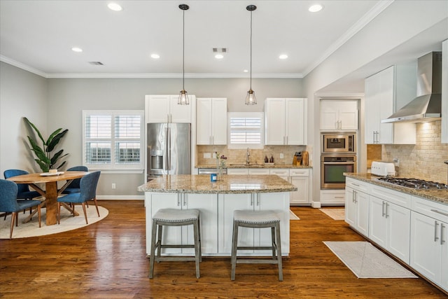 kitchen featuring dark wood finished floors, wall chimney range hood, ornamental molding, and stainless steel appliances