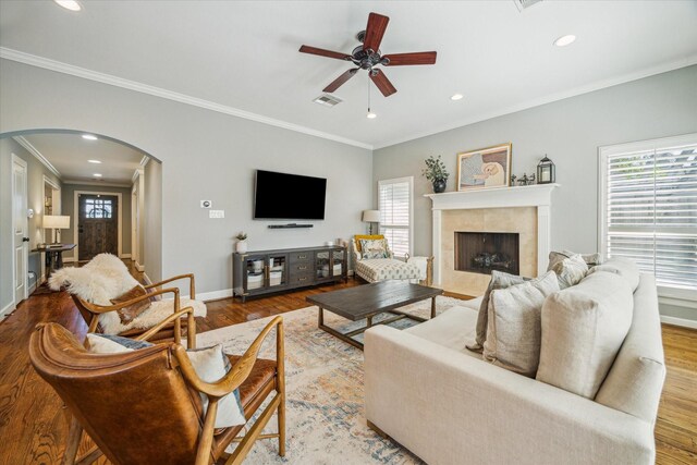 living room featuring arched walkways, a wealth of natural light, and wood finished floors