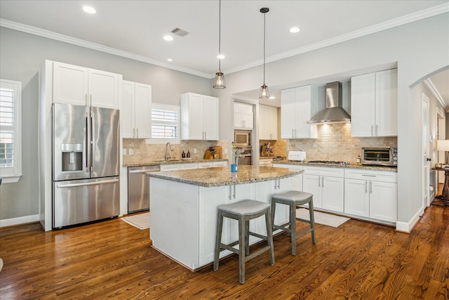 kitchen featuring crown molding, appliances with stainless steel finishes, wall chimney exhaust hood, and a sink