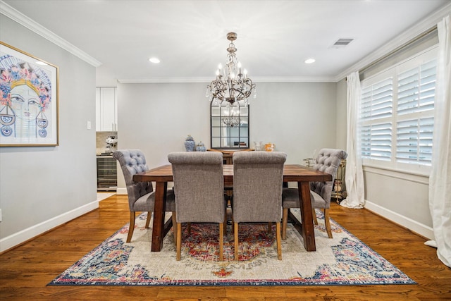 dining space featuring visible vents, crown molding, baseboards, an inviting chandelier, and wood finished floors