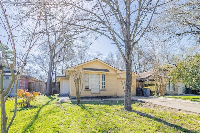 view of front of property featuring concrete driveway, fence, brick siding, and a front lawn