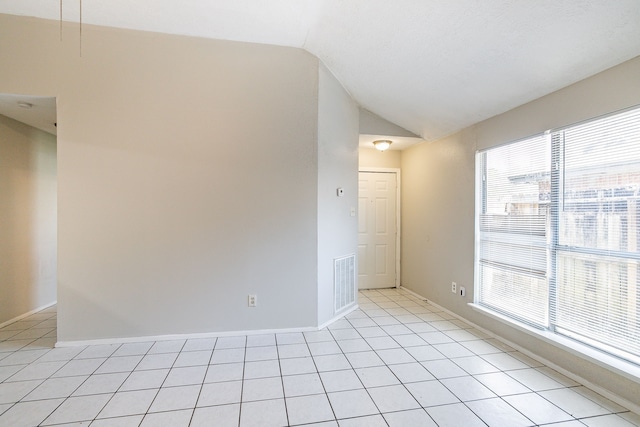 unfurnished room with light tile patterned flooring, visible vents, baseboards, and vaulted ceiling