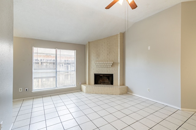 unfurnished living room with vaulted ceiling, a brick fireplace, a ceiling fan, and baseboards